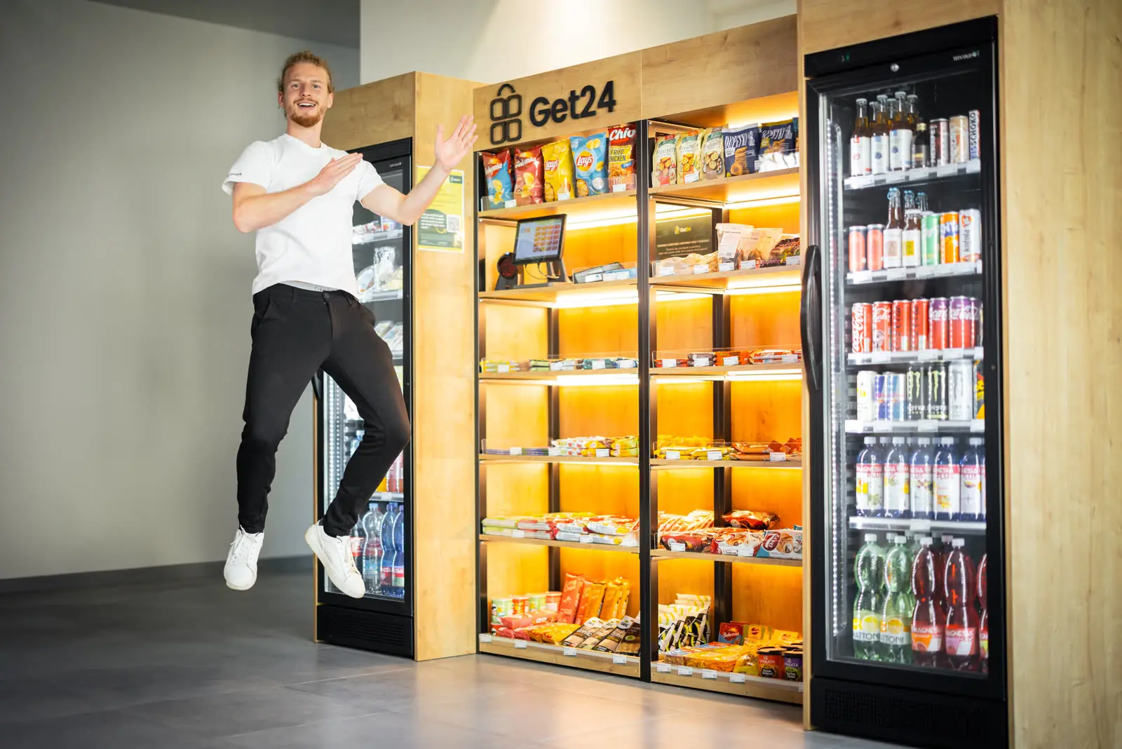 Muž radostně vyskakuje vedle nově nainstalovaného micro-marketu GET24